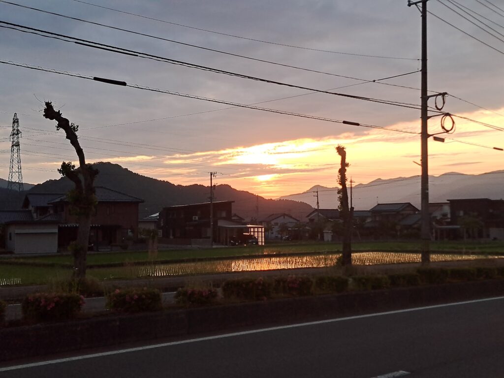 Sunset over the mountains and reflected in a race paddy field.